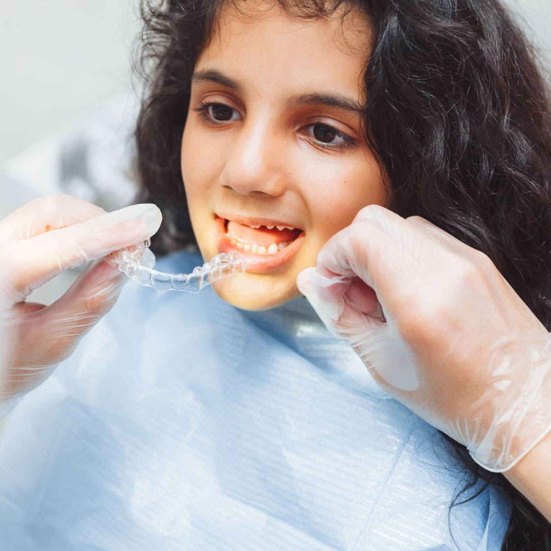 teen girl holding braces, dentist puts braces on girl. dental care and orthodontic concept.
